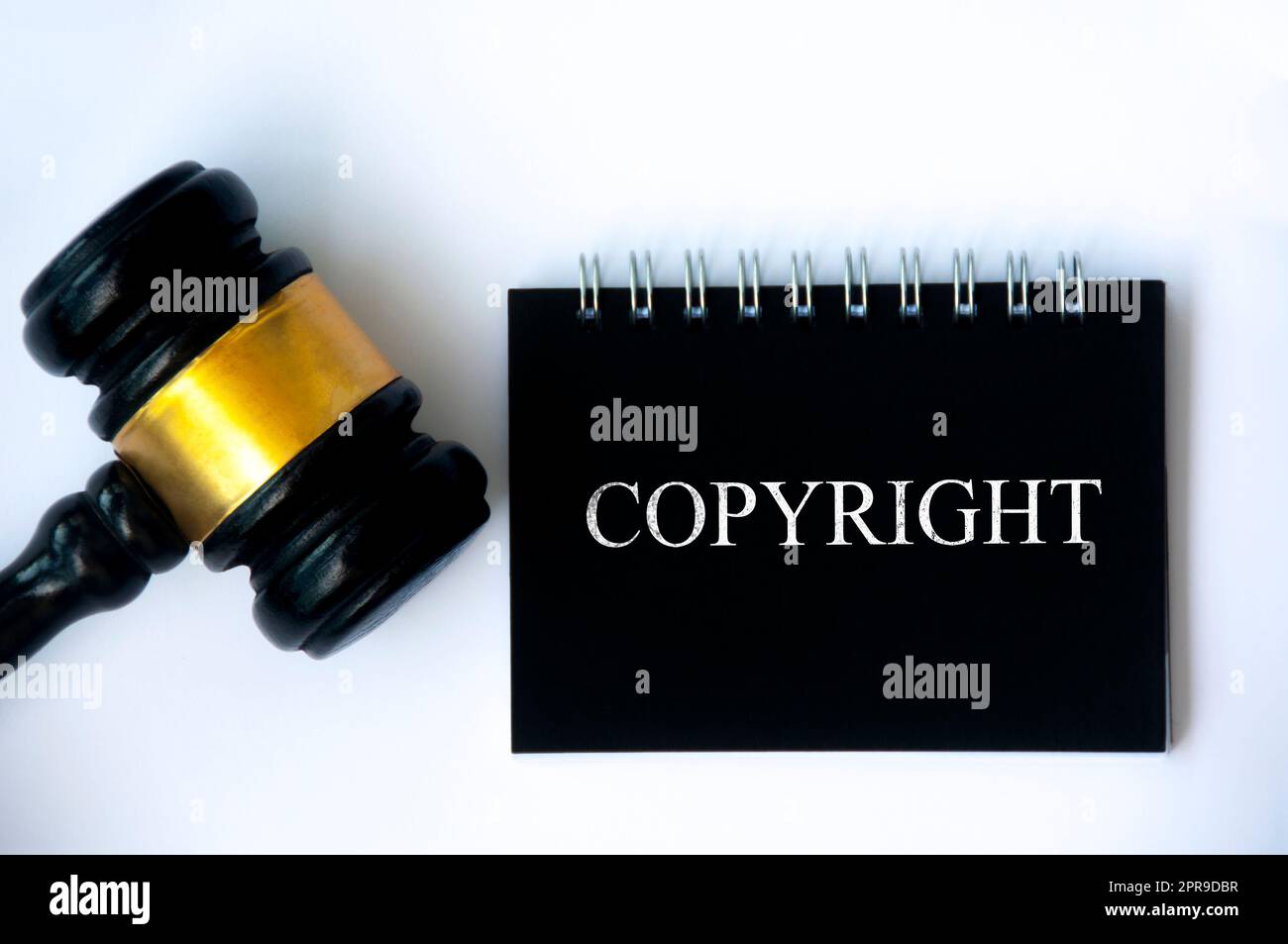 Copyright-Rechtstext auf schwarzem Notizblock und Hammer auf weißem Hintergrund. Stockfoto