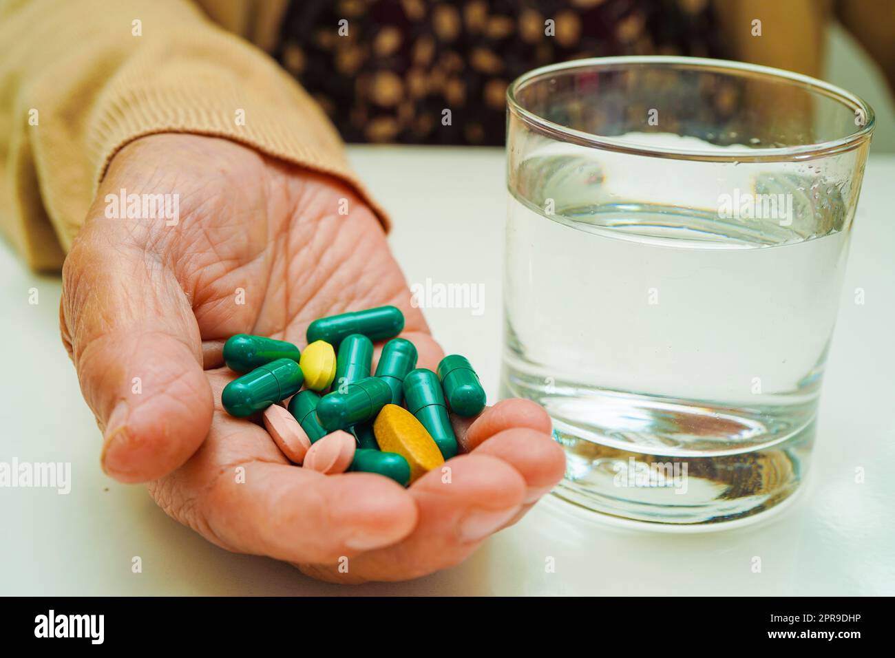 Asiatische ältere Frau hält Pille Medikament mit Wasser in Glas, stark gesundes medizinisches Konzept. Stockfoto