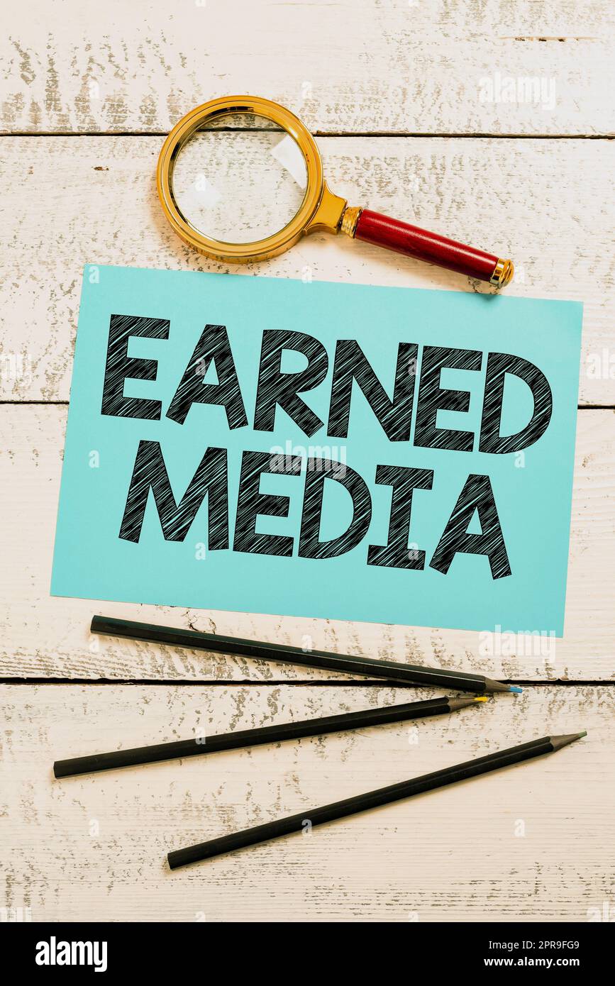 Schild mit „Earned Media“, Konzept bedeutet „Publicity“, die durch Werbemaßnahmen von Multimedia-Papier mit „New Ideas“-Lupe gewonnen wurde Stockfoto