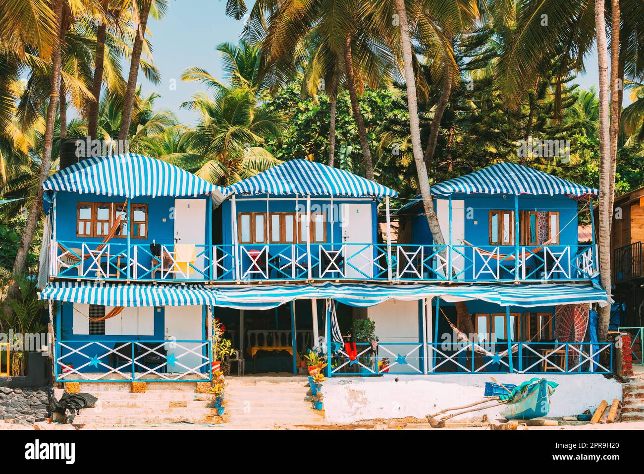 Canacona, Goa, Indien. Berühmte gemalte Gästehäuser am Strand von п vor dem Hintergrund hoher Palmen in Sonnentag Stockfoto