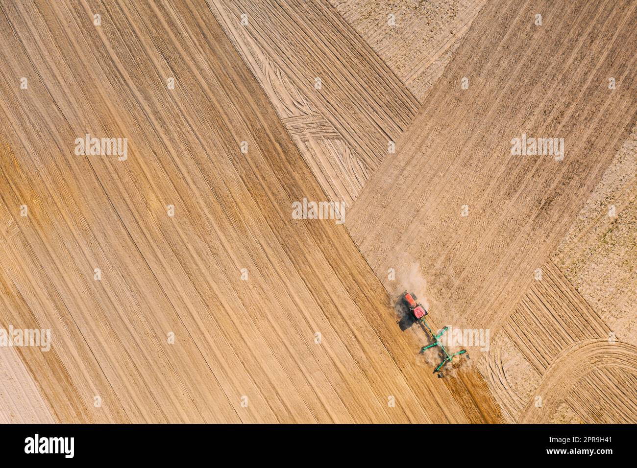 Luftaufnahme. Feld Für Das Pflügen Des Traktors. Beginn Der Landwirtschaftlichen Frühjahrssaison. Grubber gezogen von EINEM Traktor auf dem Land ländliche Feldlandschaft Stockfoto