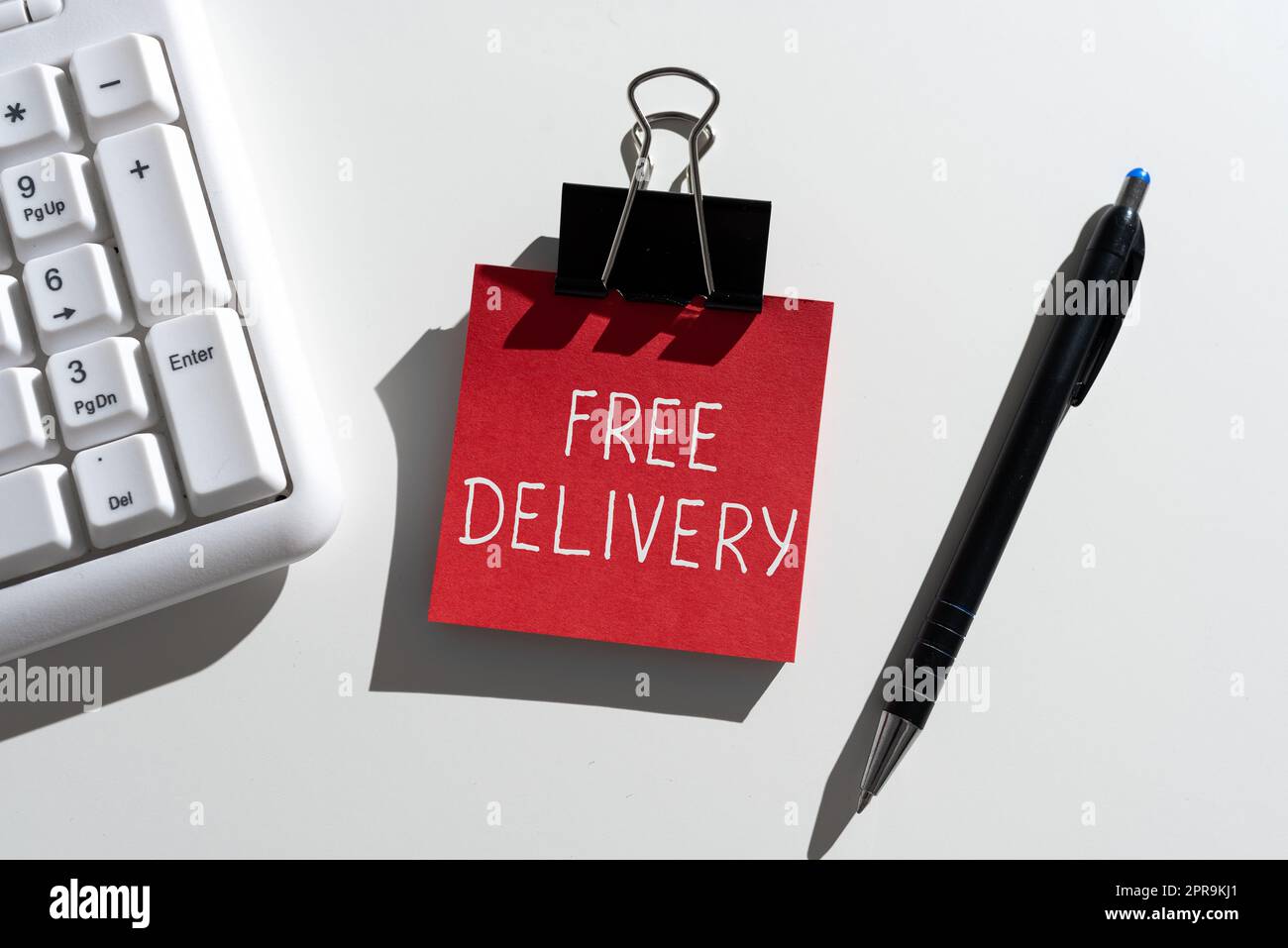 Handschriftliches Schild „Free Delivery“. Word for Shipping Package Cargo Courier Distribution Center Fragile wichtige Mitteilungen, die auf einem Notizzettel mit Stift und Tastatur verfasst sind Stockfoto