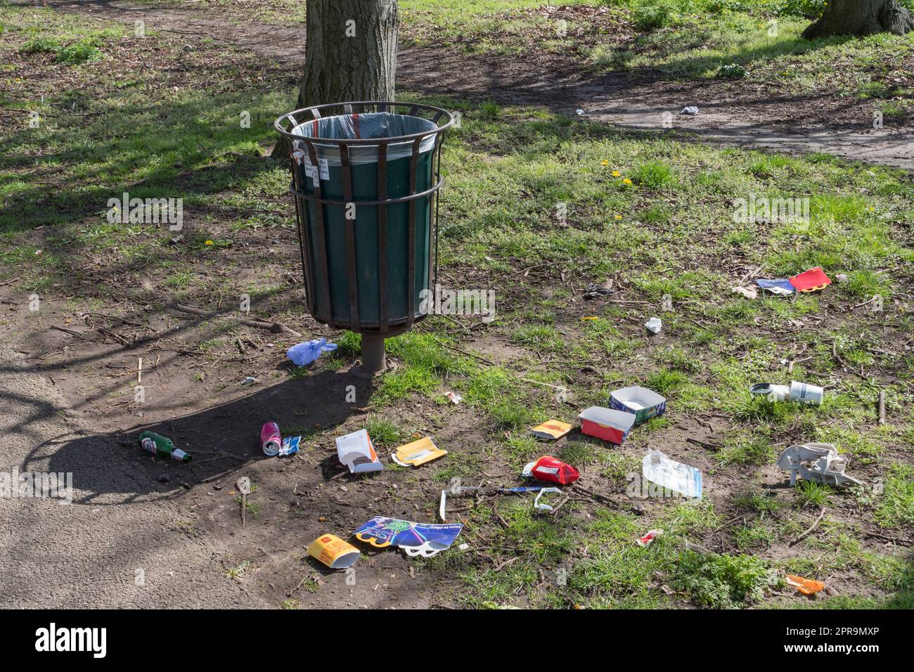 Ein fast leerer Abfalleimer mit Müll auf dem Gras um ihn herum (tierisches Chaos oder menschliches Chaos), The Old Deer Park (Richmond Park), London, UK Stockfoto