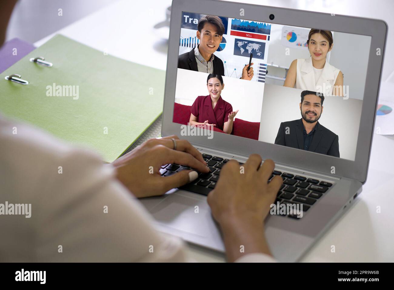 Rückansicht einer Geschäftsfrau im braunen Anzug, die am Schreibtisch im Büro sitzt und die Tastatur eines Laptops eingibt, mit einer weißen Videokonferenz und einem Online-Meeting mit einem Geschäftspartner. Stockfoto