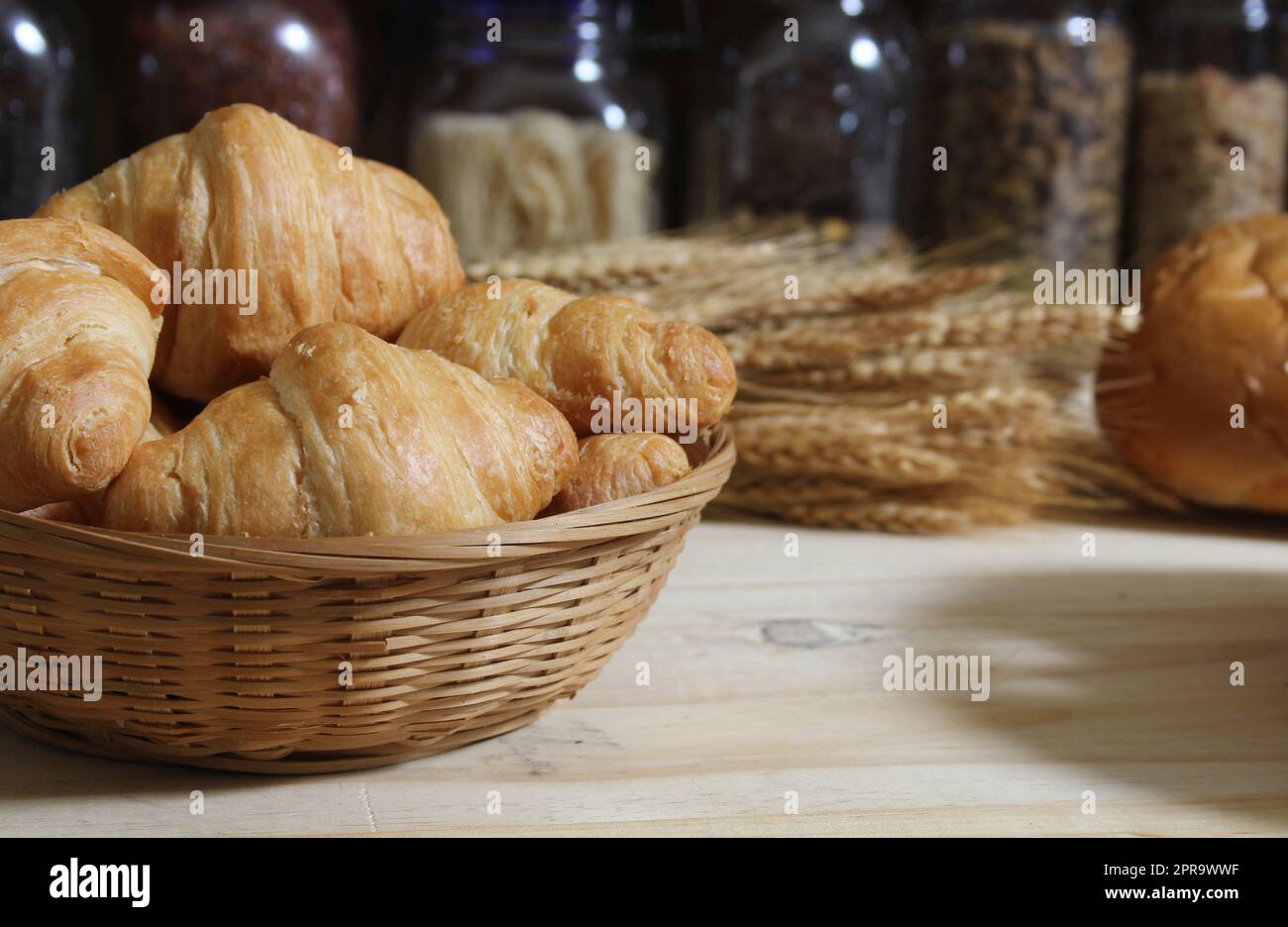 Frisch gebackenes Brot in der rustikalen Küche auf einem Holztisch mit Gläsern mit getrockneten Speisen im Hintergrund mit flachem DOF Stockfoto
