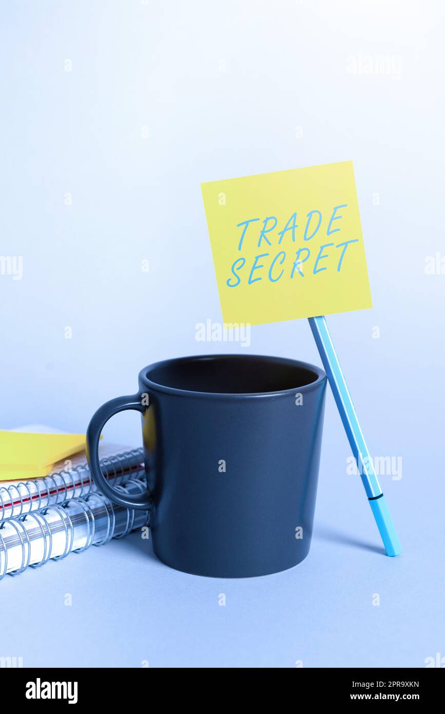 Schild mit Betriebsgeheimnis. Word for Confidential Informationen über ein Produkt Intellectual Property Cup, Stift, Notizbücher und Haftnotizen mit wichtiger Ankündigung am Schreibtisch. Stockfoto