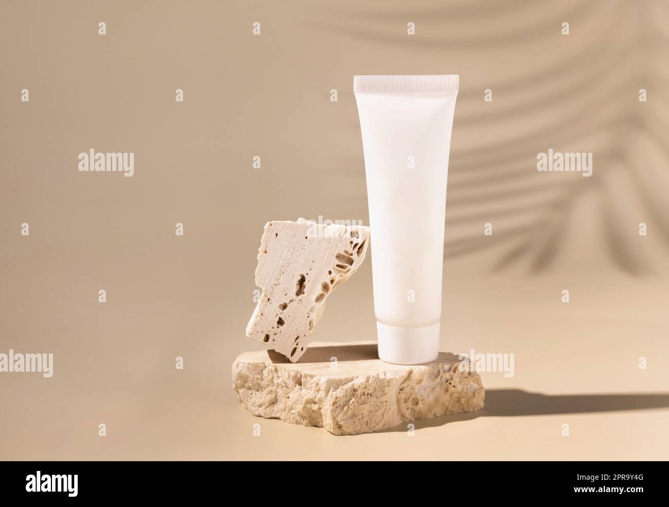 Weiße cremefarbene Kunststoffröhre auf Stein auf hellgelben, Palmenblätter harte Schatten. Modell Stockfoto