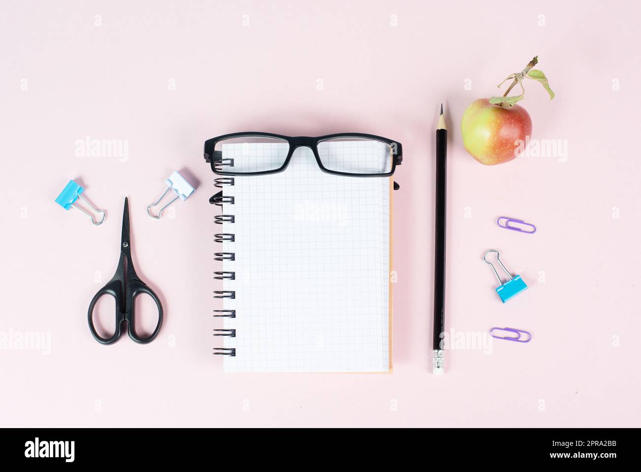 Leeres Notizbuch mit Stift, Brille und Apfel auf einem pastellfarbenen Schreibtisch, Brainstorming für neue Ideen, Schreiben einer Botschaft, Home Office und Bildungskonzept Stockfoto
