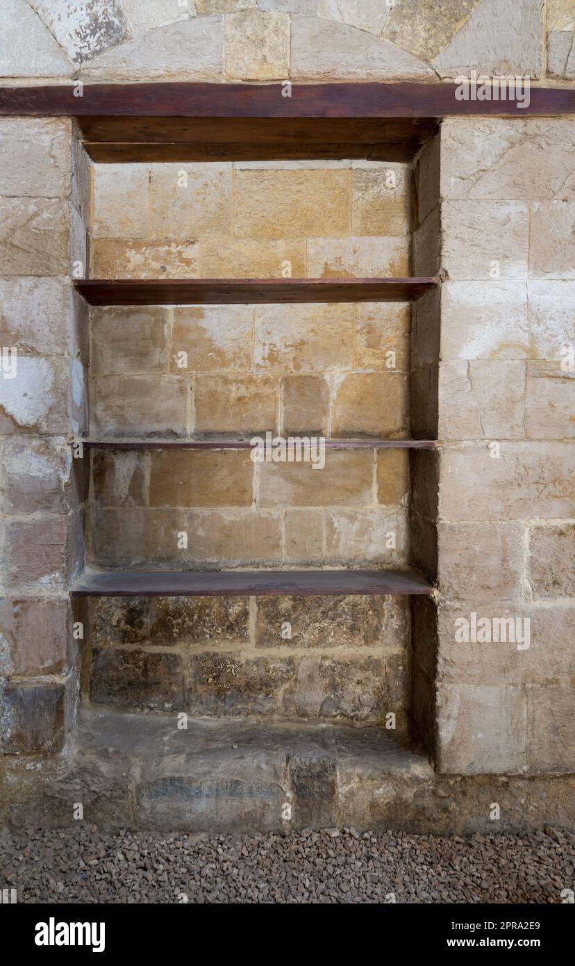 Versenkter Rahmen, Nische mit Holzregalen in einer alten Grunge-Stein-Mauer Stockfoto