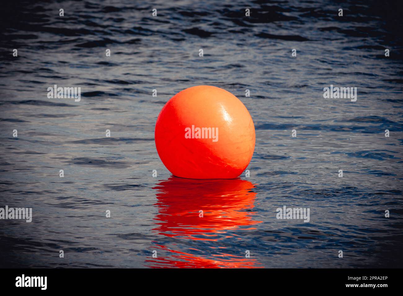 Orangenboje schwimmt auf dunklem, dramatischem Meerwasser Stockfoto