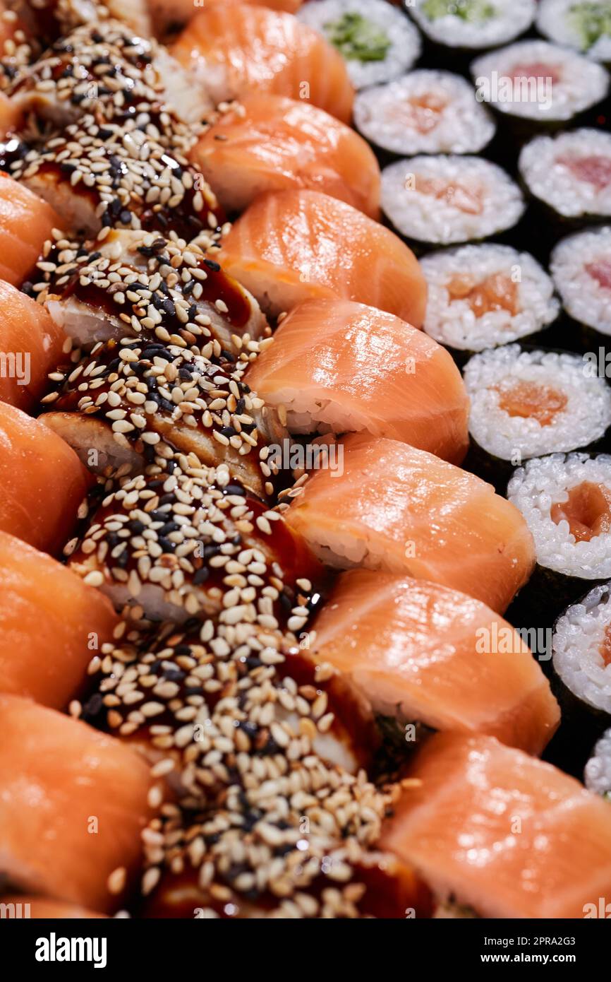 Großes Set mit Reihen verschiedener Sushi-Brötchen mit unterschiedlichen Füllungen. Stockfoto