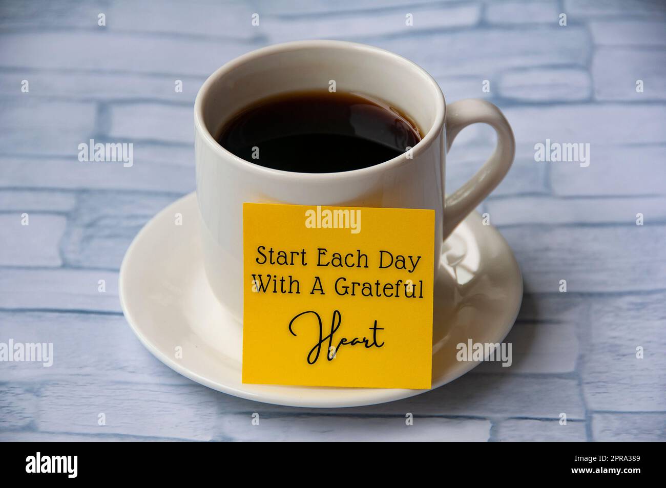 Inspirierender Zitattext auf gelbem Notizblock auf der Kaffeetasse – Beginnen Sie jeden Tag mit einem herzlichen Dankeschön. Motivationskonzept Stockfoto