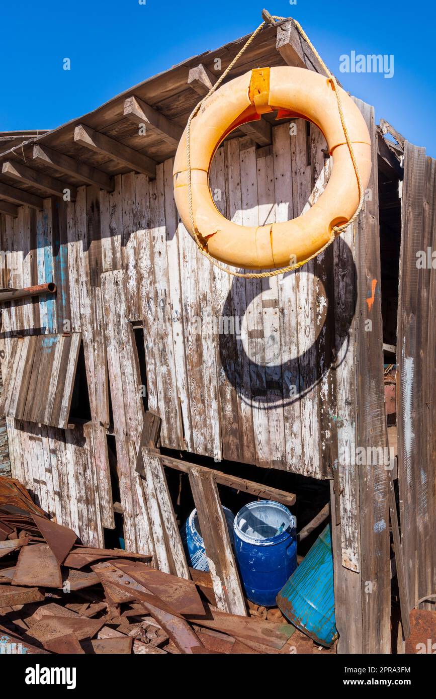 Ein alter orangefarbener Lebensretter hing am Rand des Daches eines schäbigen kleinen Holzgebäudes zwischen vielen Brettern Stockfoto
