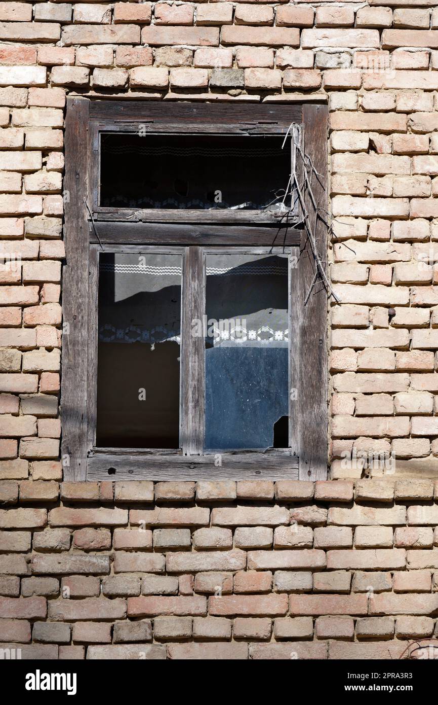 Detail eines alten zerbrochenen Fensters an einer Ziegelwand Stockfoto