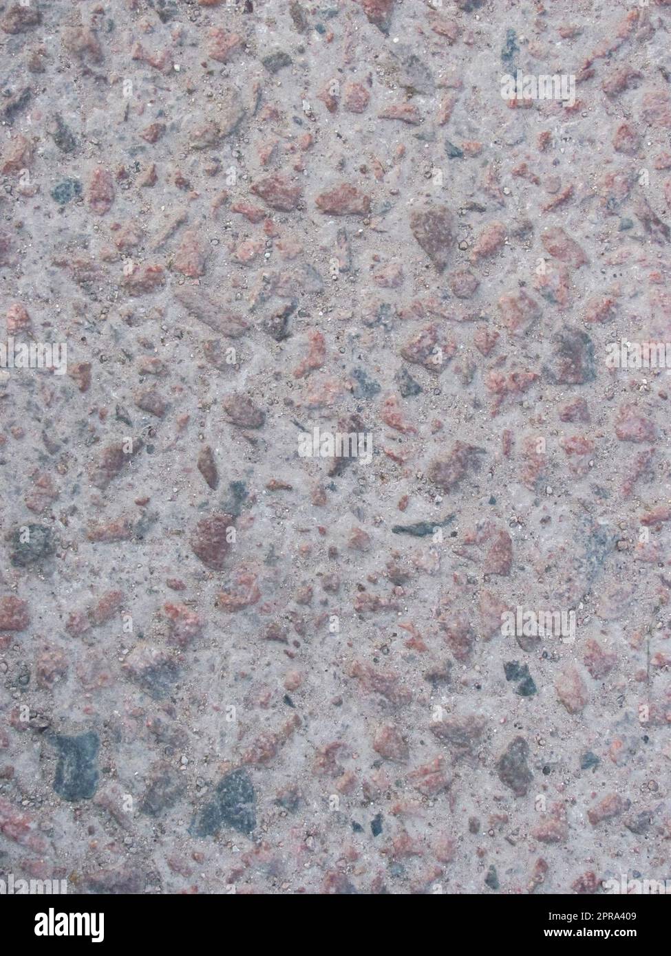 Die raue Betonstruktur mit Flecken aus rotem Granit Stockfoto