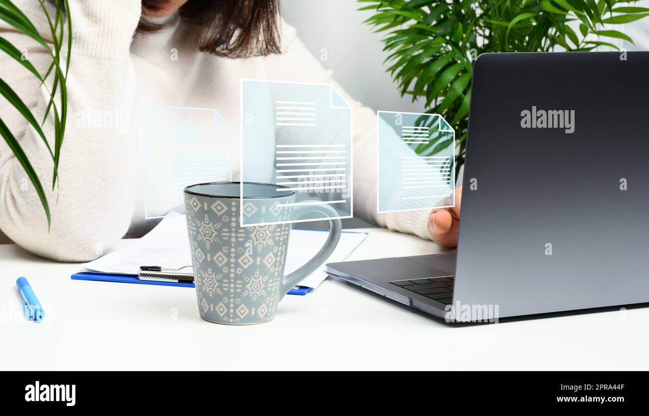 Frau sitzt an einem Tisch und arbeitet an einem Laptop, dem Rekrutierungsprozess. Stockfoto