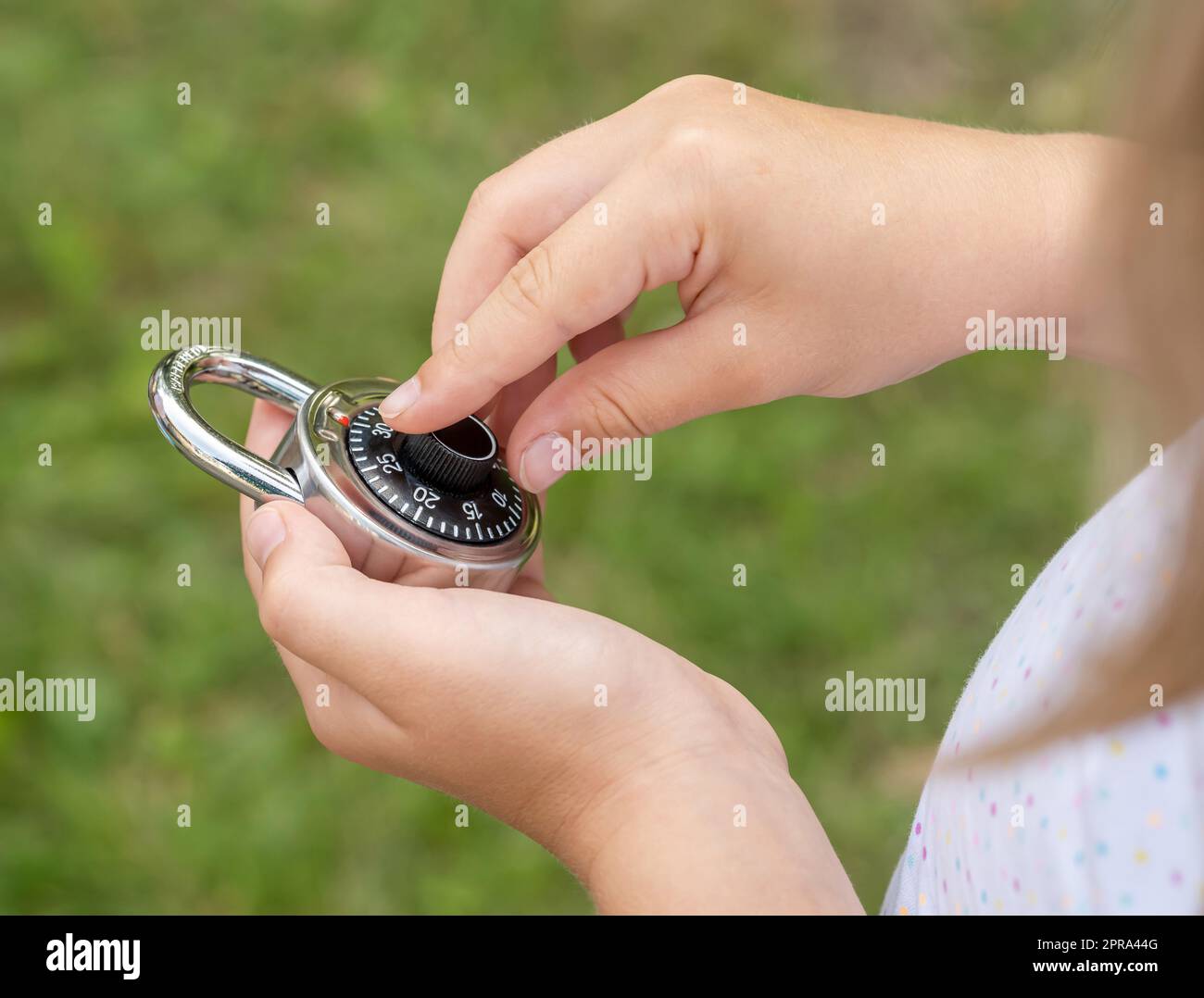 Das Kind entsperrt ein einfaches geschlossenes Schloss, das ein Codeschloss in der Hand hält. Kennwort knacken, Ver- und Entschlüsselung, Hacking, Knacken abstrakt Stockfoto