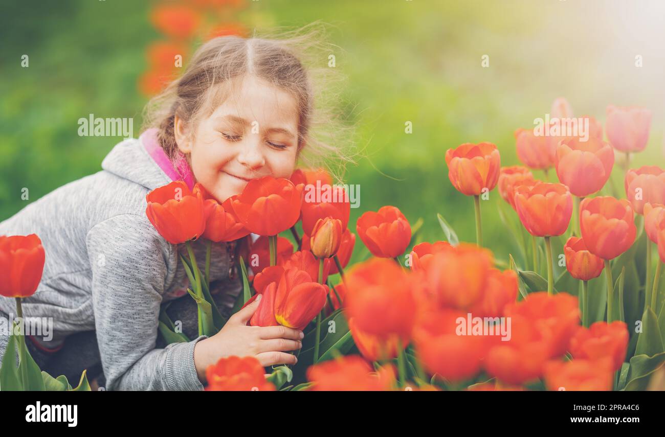 Nettes Mädchen pflücken rote Tulpen im Strauß im Garten. Stockfoto