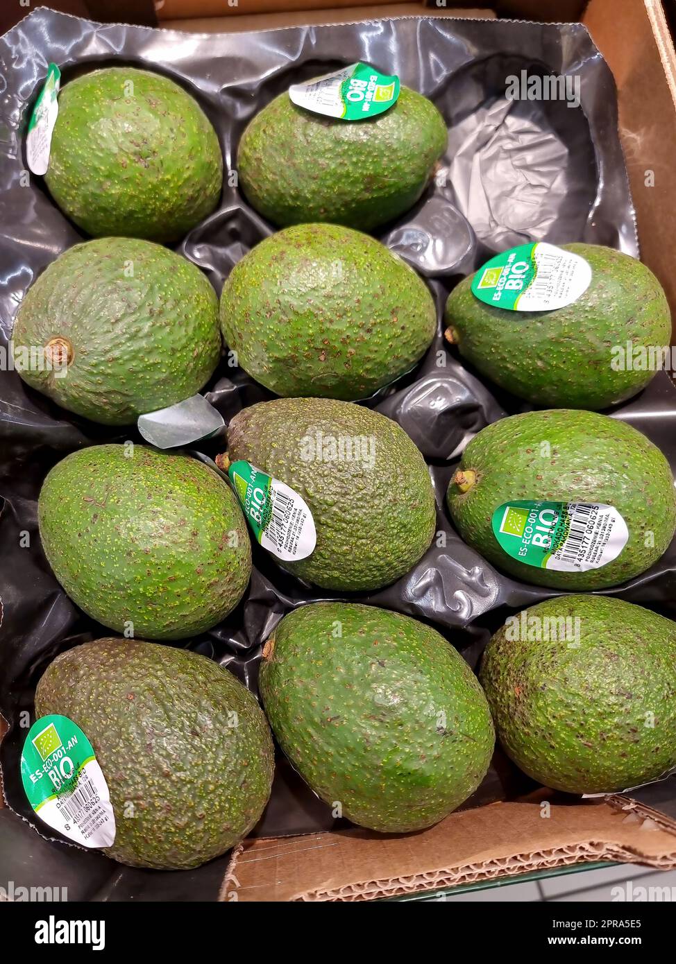 Beschriftete unreife Avocados, ein Satz Avocadofrüchte in einer Kiste in einem Supermarkt, niemand, Objektdetails, Nahaufnahme. Avocado gekauft, Lebensmittelpreise c Stockfoto
