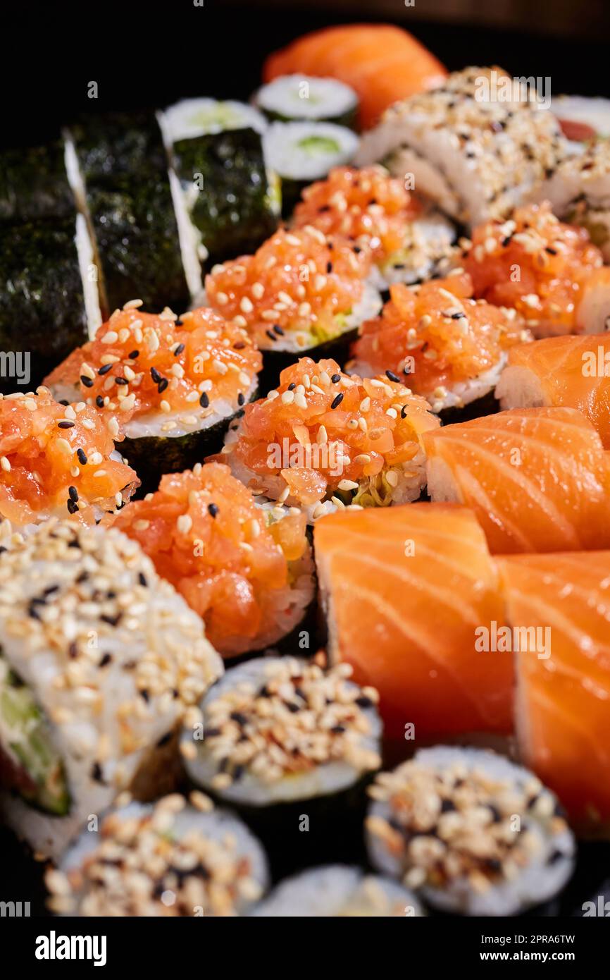 Nahaufnahme einer Reihe von Sushi-Gattungen mit rohem Lachs und Sesamsamen. Stockfoto