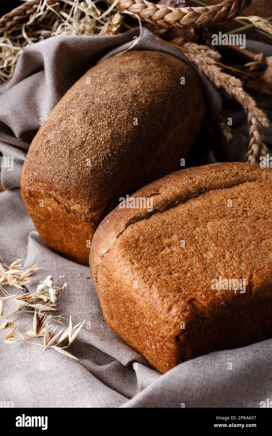 Land Stillleben, auf dem zwei Laibe von frischem hausgemachtem Roggenbrot liegen auf Sackleinen Tuch. Stockfoto