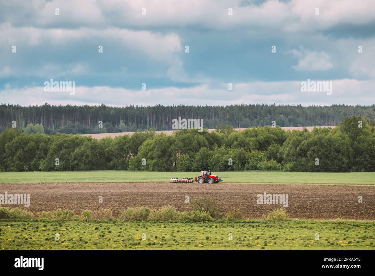 Pflügen Von Traktoren In Der Frühlingssaison. Beginn Der Landwirtschaftlichen Frühjahrssaison. Kultivator, der von Einem Traktor auf dem Land gezogen wird. Landschaftsbild Ländlicher Felder Stockfoto