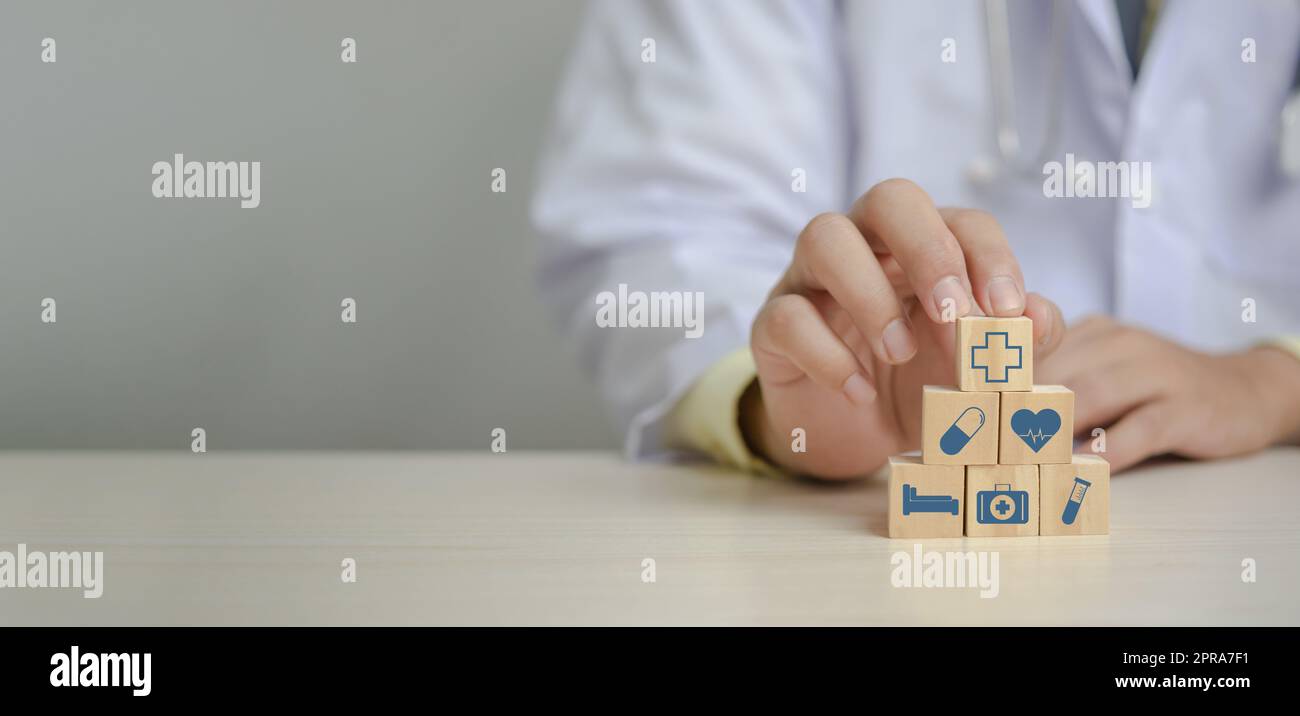 Arzt Putting und Stapeln Holzblock Würfel Symbol medizinische Versorgung auf dem Tisch Panorama Hintergrund Konzept. Stockfoto