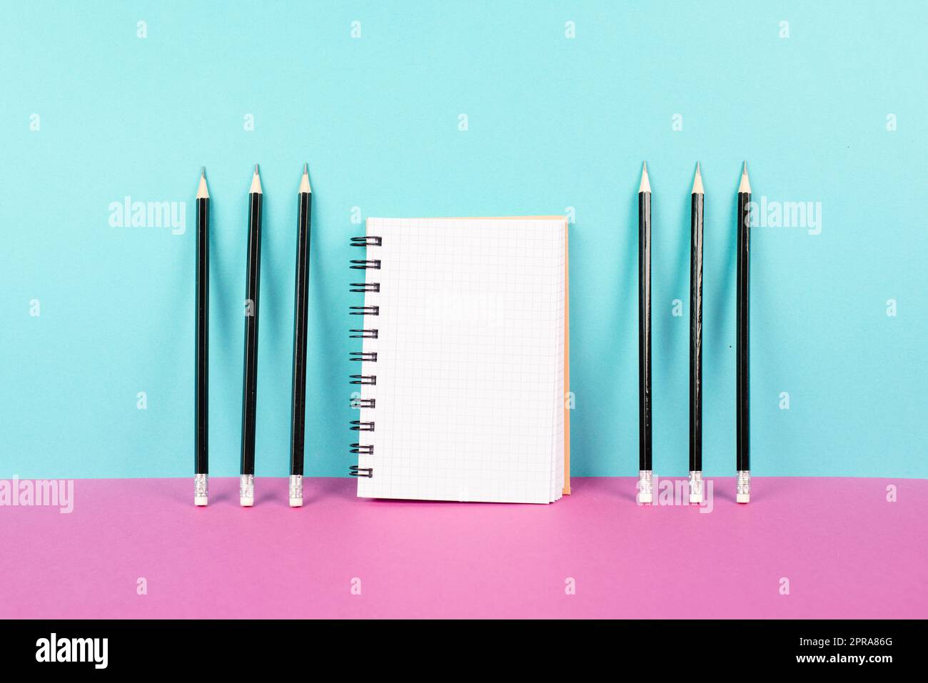 Leeres Notizbuch mit Bleistiften auf einem rosa und blauen Hintergrund, Brainstorming für neue Ideen, Schreiben einer Nachricht, Schreibtisch im Home Office Stockfoto
