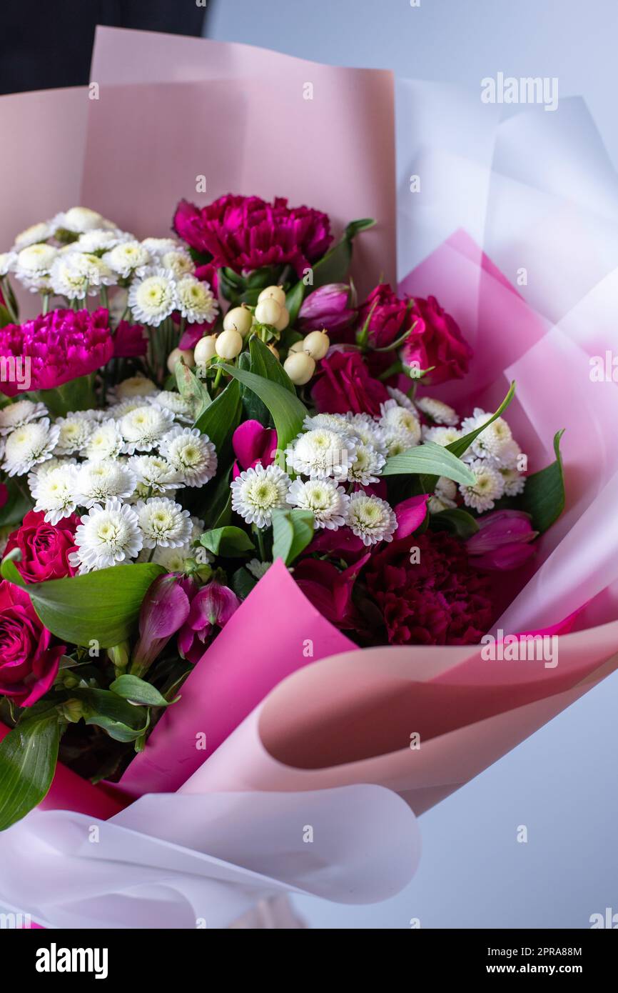 Nahaufnahme eines Bouquets aus rosa und weißen Blumen, eingewickelt in florales Pauspapier. Stockfoto