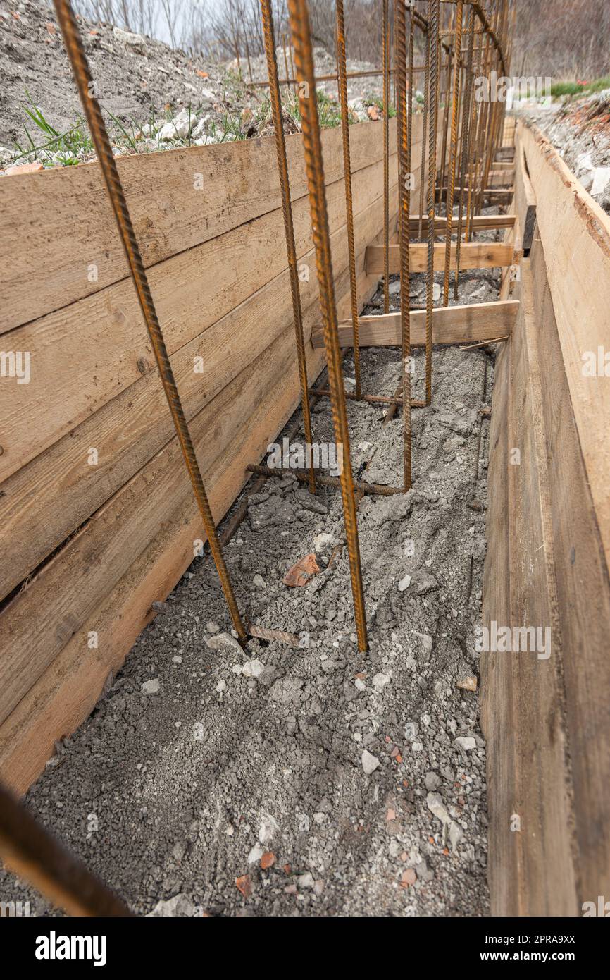 Verstärkung eines flach vergrabenen Streifenfundaments eines flachen Wohngebäudes, der Graben ist mit Erde bedeckt Stockfoto