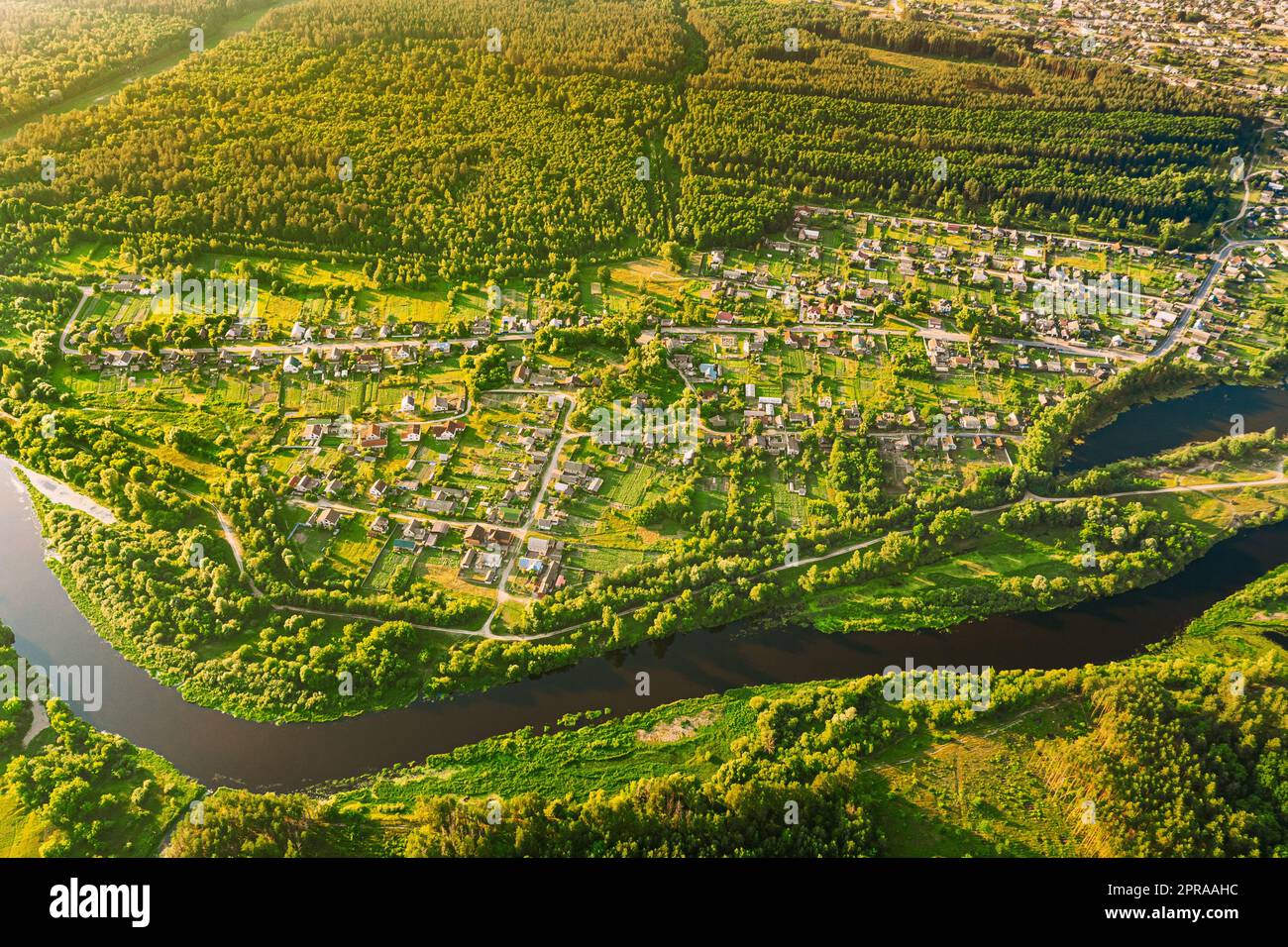 Luftaufnahme Des Calm River And Village In Weißrussland, Europa. Grüne Waldlandschaft Am Sonnigen Sommerabend. Blick Von Oben Auf Die Wunderschöne Europäische Natur Von High Attitude. Drohnenansicht. Vogelperspektive Stockfoto