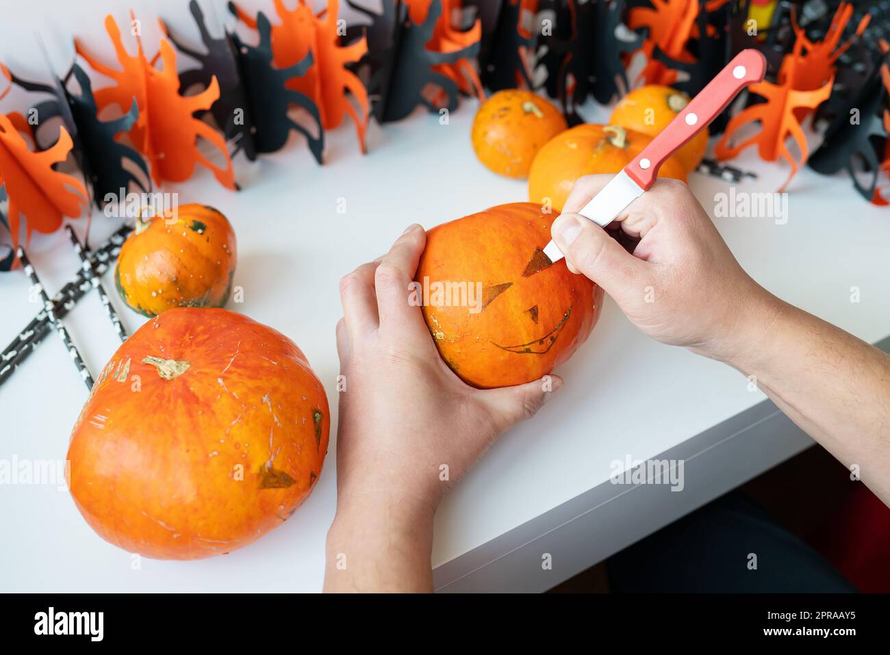 Halloween 31. Oktober. Ein Mann schneidet das Gesicht eines Kürbiss mit einem Messer. Blick von oben. Stockfoto