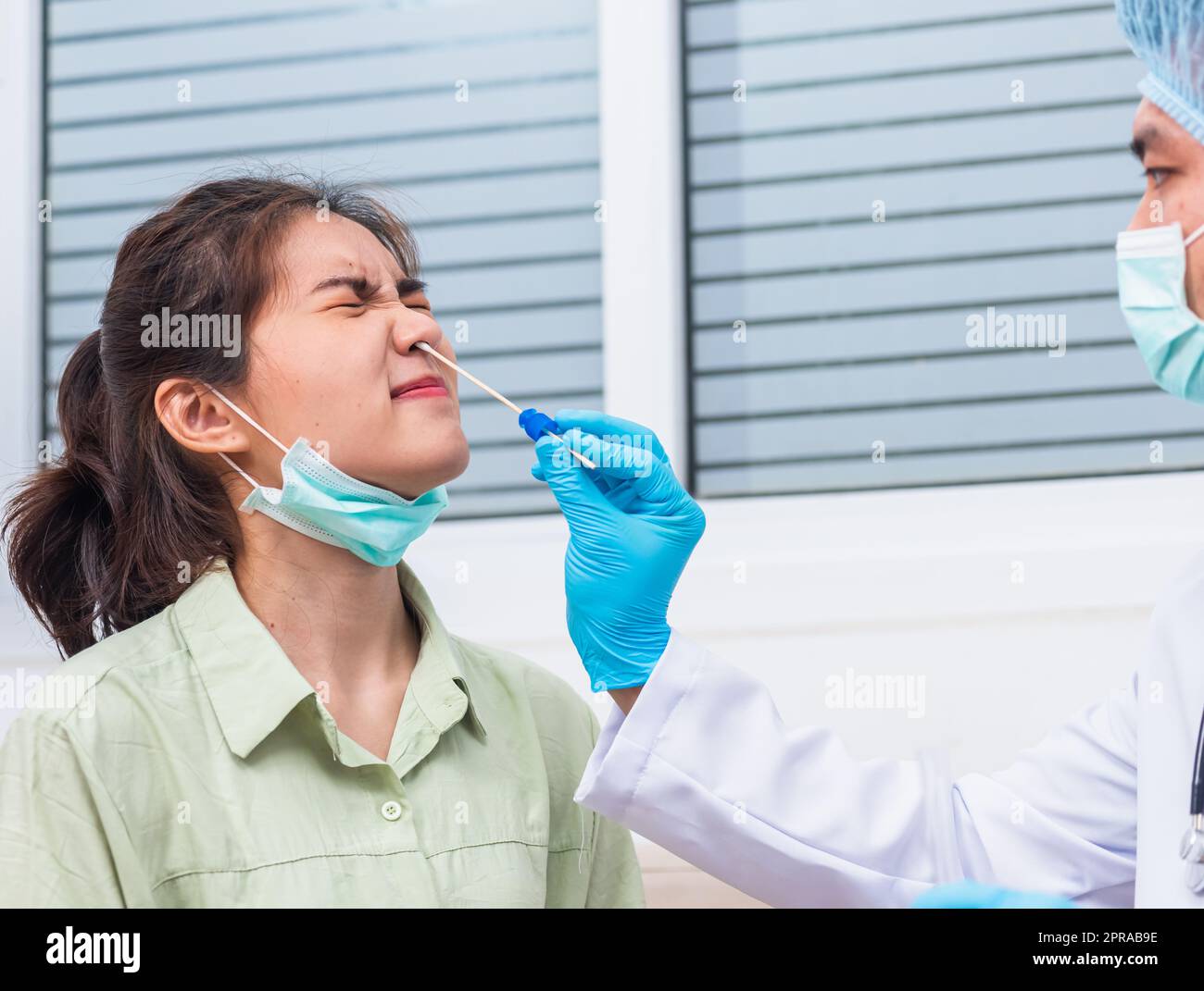 Doktor man nehmen Speichelprobe durch die Nase mit Wattestäbchen, um Coronavirus-Test von einer jungen asiatischen Frau zu überprüfen Stockfoto
