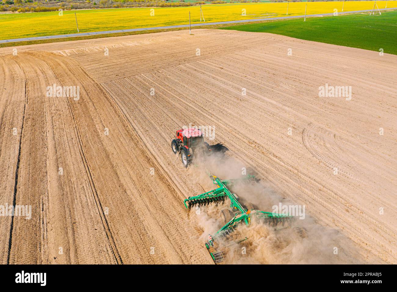 Luftaufnahme. Pflügen Des Traktors. Beginn Der Landwirtschaftlichen Frühjahrssaison. Kultivator, gezogen von Einem Traktor in ländlicher Ackerlandschaft. Staub Steigt Unter Dem Pflug Auf Stockfoto