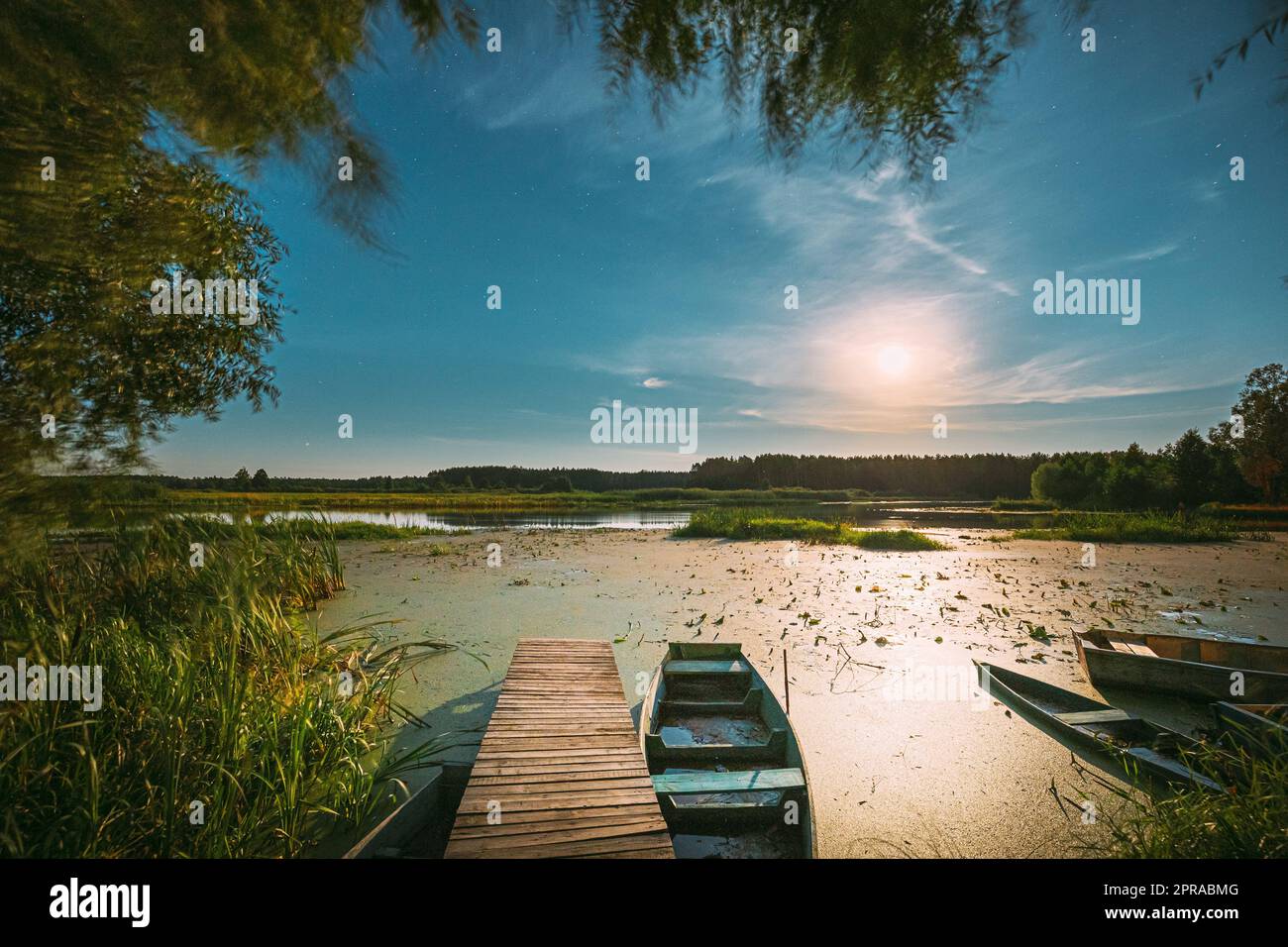 Echte Nachthimmel Stars Und Mondaufgang Über Dem Alten Pier Mit Verankertem Hölzernen Fischerboot. Natürlicher Sternenhimmel Und Landschaftslandschaft Mit Lake River Am Frühen Frühlingsabend. Russische Natur Stockfoto