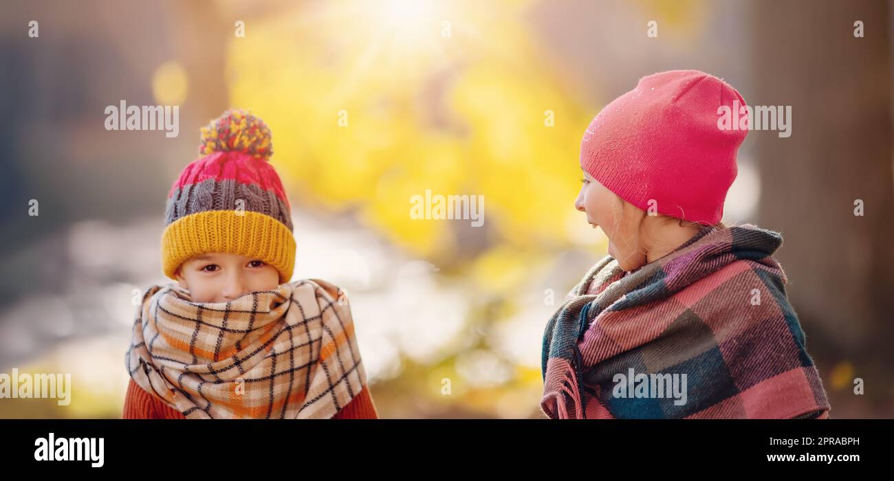 Kinder in warmen Hüten und Tüchern stehen im herbstlichen Park. Stockfoto