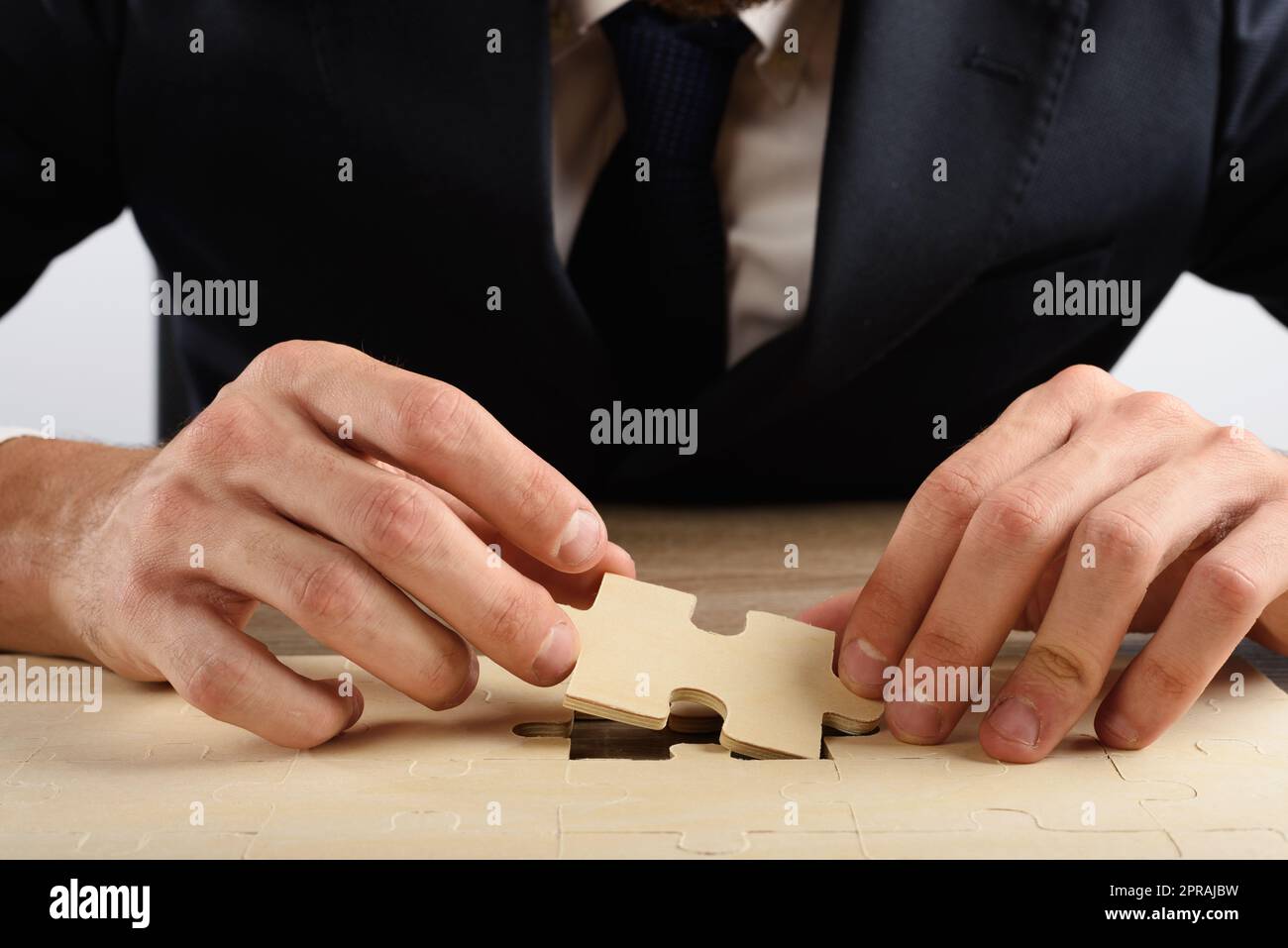 Geschäftsmann wendet den letzten Teil eines fehlenden Puzzles an Stockfoto