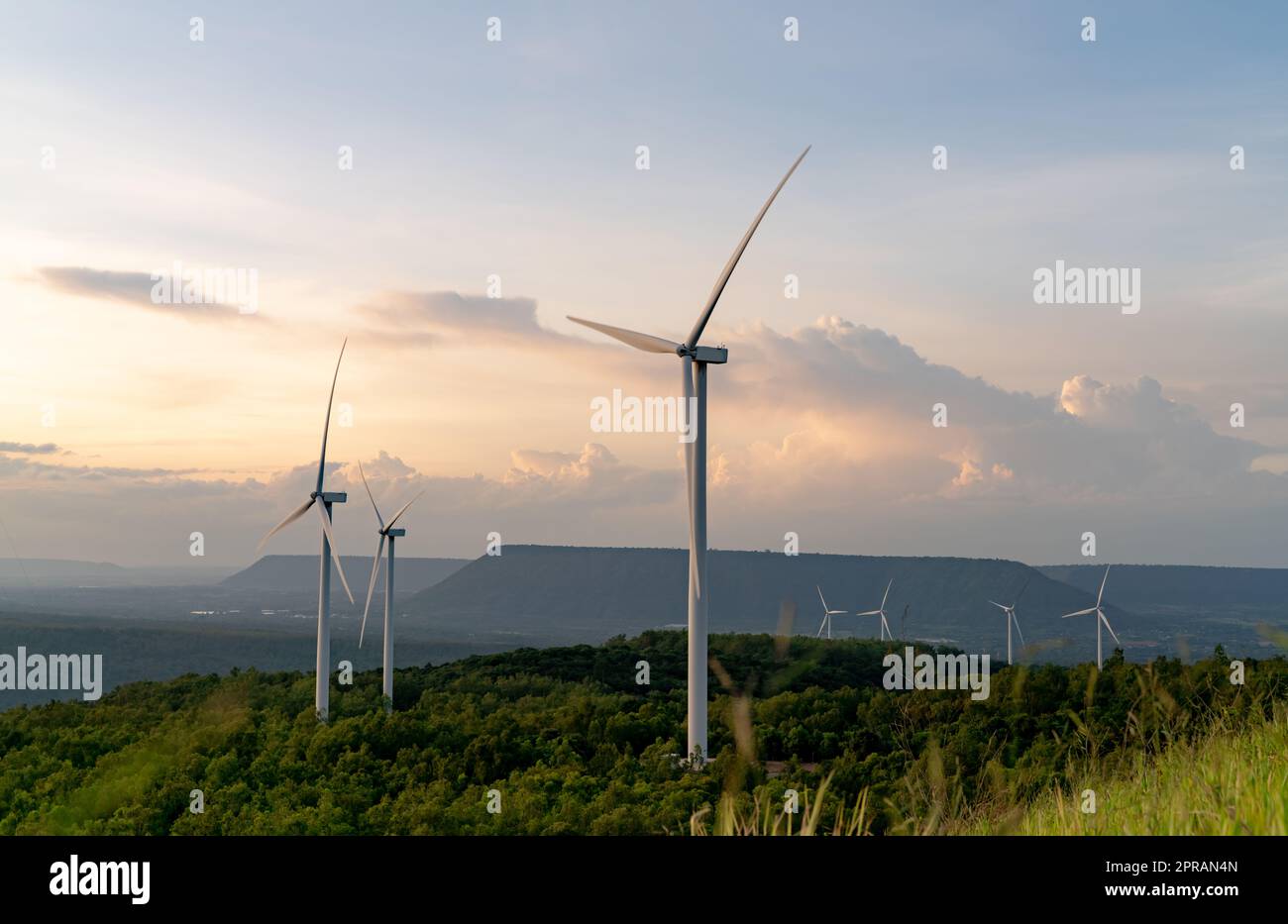 Windenergie. Windkraft. Nachhaltige, erneuerbare Energien. Windturbinen erzeugen Strom. Windmühlen-Farm auf dem Berg mit Sonnenuntergang am Himmel. Umweltfreundliche Technologie. Erneuerbare Ressource. Nachhaltige Entwicklung. Stockfoto