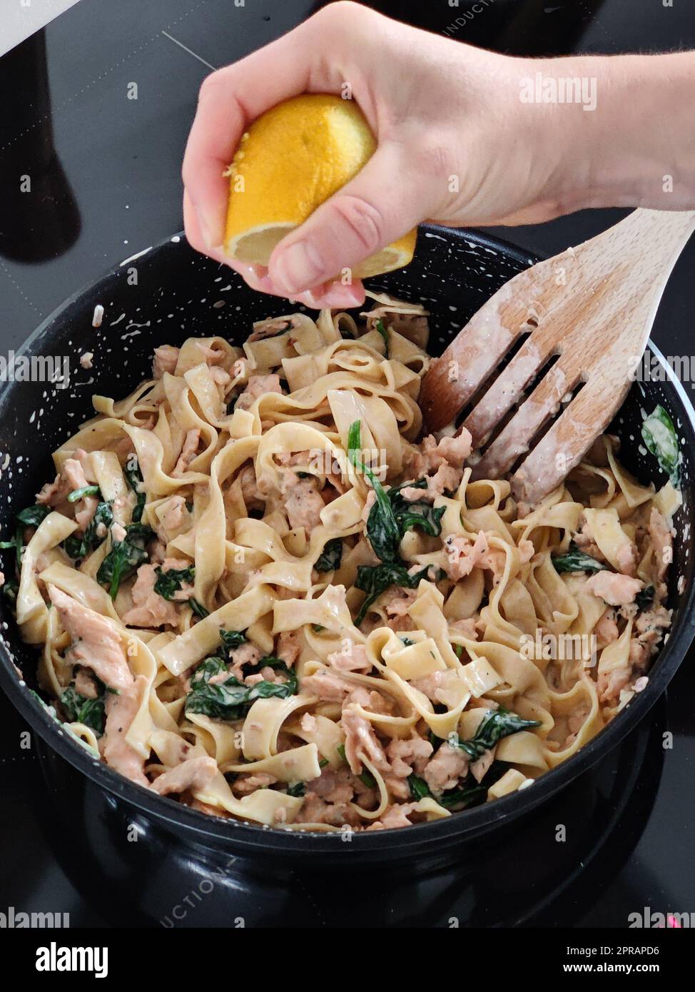 Frau drückt eine Zitrone auf leckere hausgemachte Meeresfrüchte-Pasta in der eigenen Küche, Nahaufnahme Stockfoto