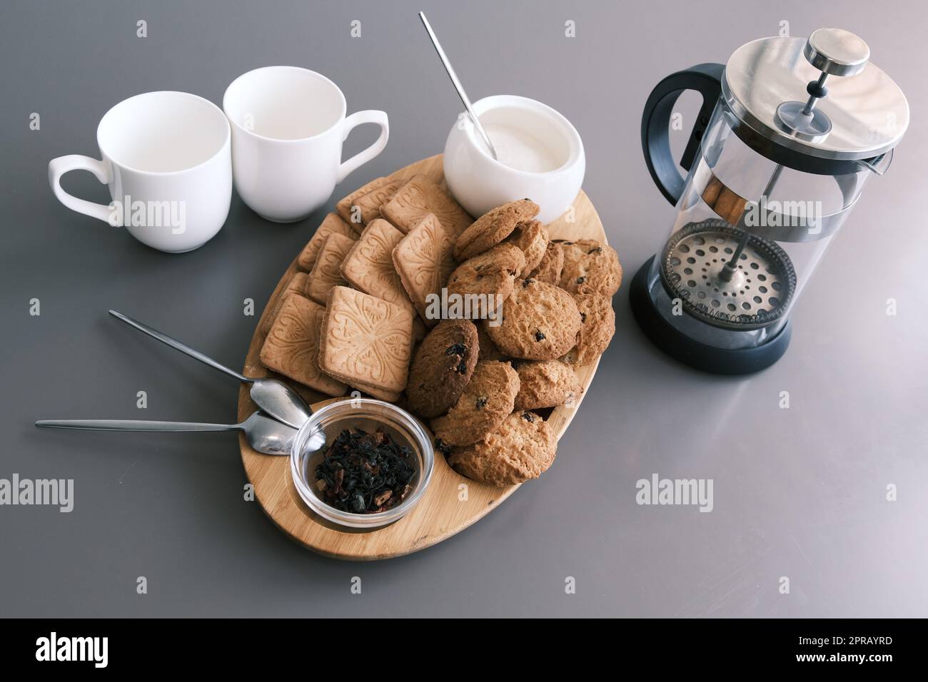 Ein leckerer Snack, zwei Tassen schwarzen Tee und ein Teller Haferbrei-Kekse, ein Holzbrett auf grauem Hintergrund, Blatttee. Stockfoto