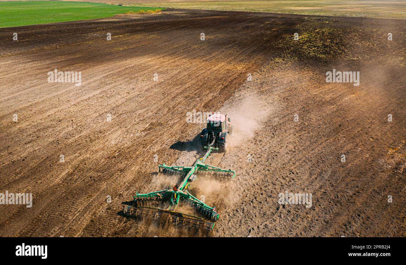 Luftaufnahme. Pflügen Des Traktors. Beginn Der Landwirtschaftlichen Frühjahrssaison. Kultivator, gezogen von Einem Traktor in ländlicher Ackerlandschaft. Staub Steigt Unter Dem Pflug Auf Stockfoto
