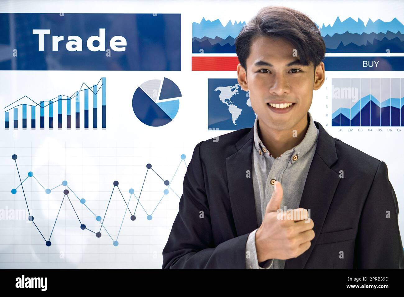 Junger asiatischer Geschäftsmann in schwarzem Anzug hebt den Daumen vor dem Präsentationsmonitor hoch. Stockfoto