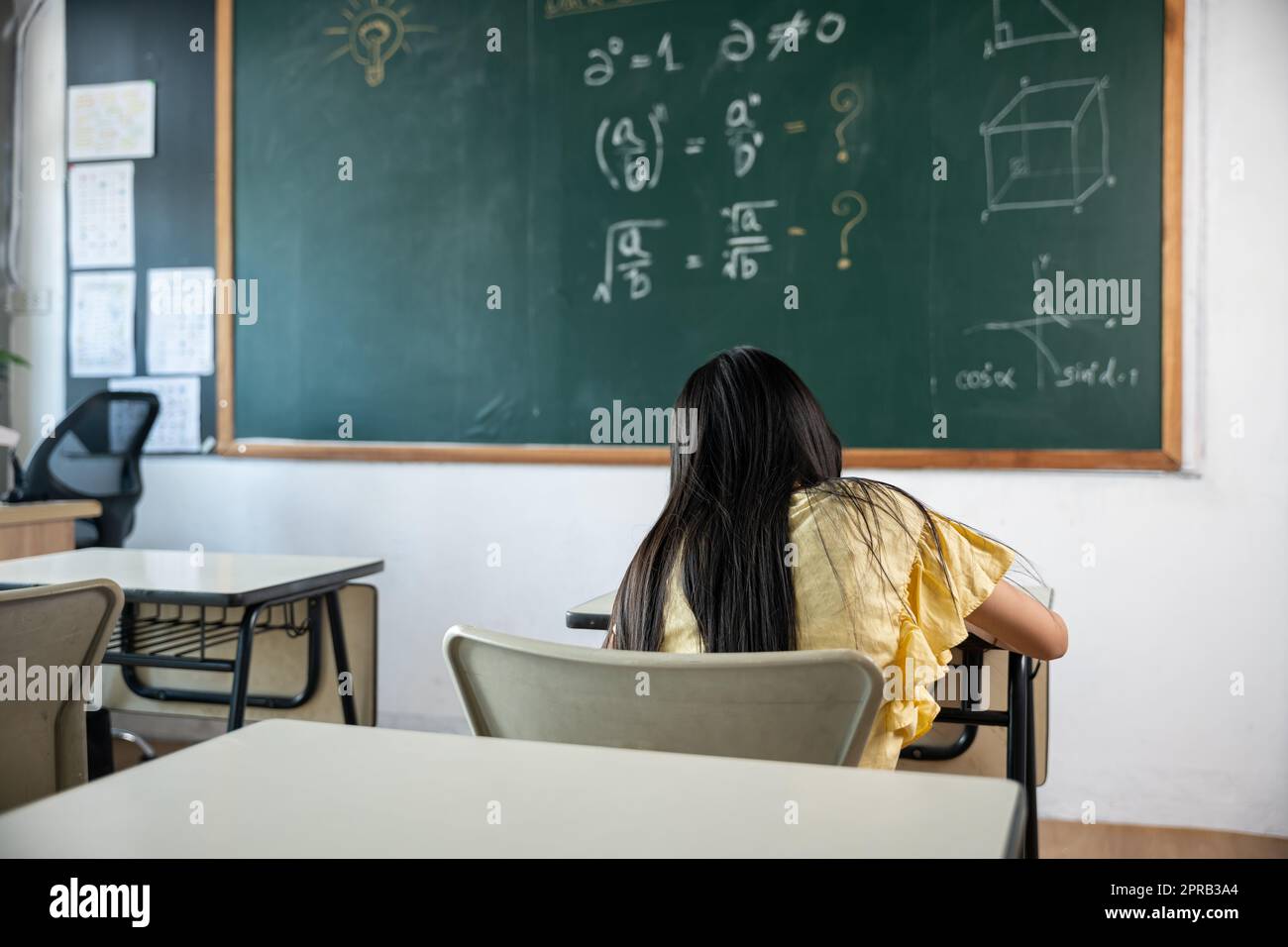 Rückansicht eines Schulmädchens, das im Klassenzimmer Unterricht nimmt, und hart arbeitende Arbeit an der Tafel schreibt Stockfoto