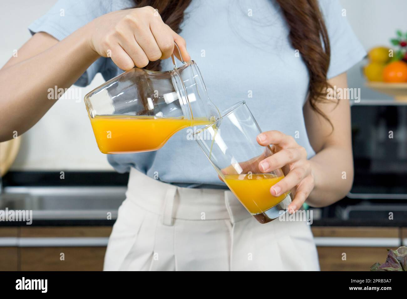 Closeup weibliche Hand Gießen Sie gemischte Früchte und Veggie Smoothie aus Glas in Glas. Stockfoto