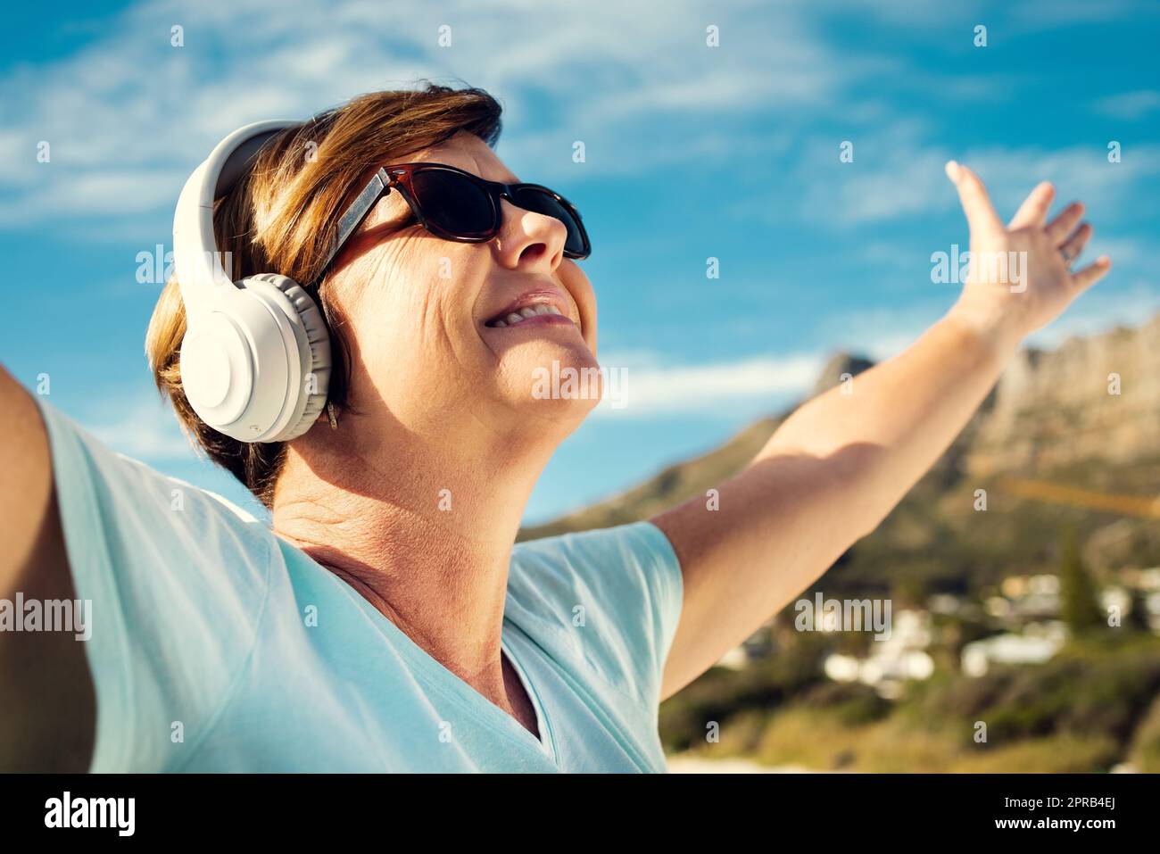 Musik ist wirklich die beste Stimmungsverbesserung. Eine Frau trägt Kopfhörer, während sie im Freien steht. Stockfoto