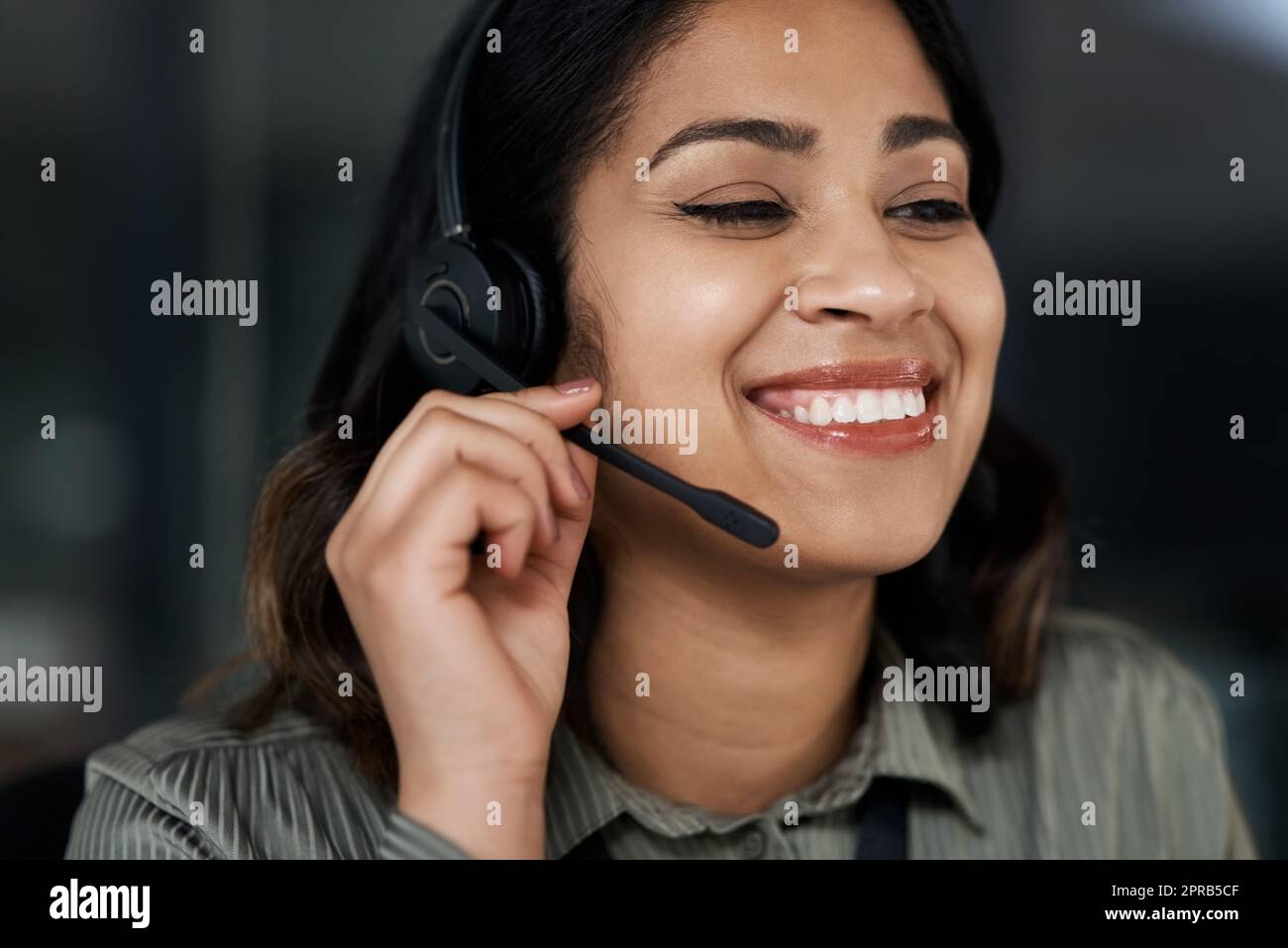 Eine junge Geschäftsfrau, die ein Headset trägt, während sie in einem Callcenter arbeitet. Stockfoto