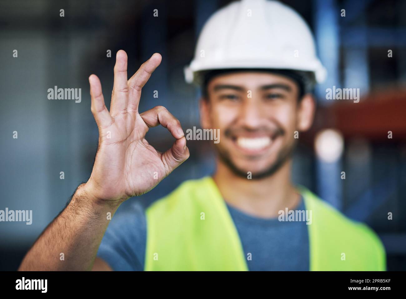 Wurden 100 Sicherheitsbestimmungen erfüllt. Porträt eines jungen Mannes, der auf einer Baustelle eine gute Geste zeigt. Stockfoto