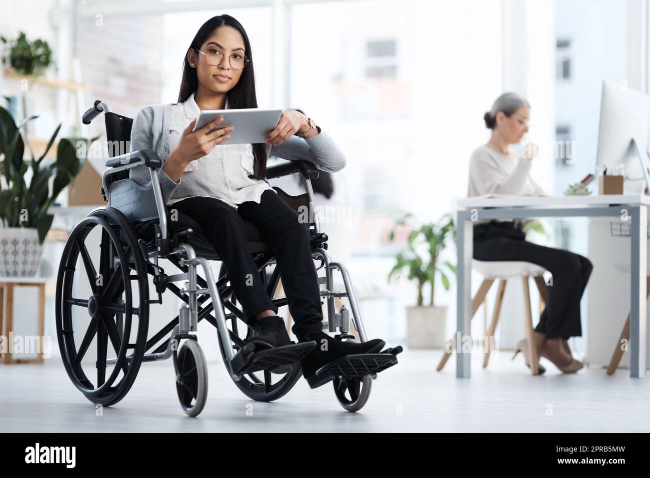 Auf Erfolg ausgerichtet. Ganzkörperportrait einer attraktiven jungen Geschäftsfrau im Rollstuhl, die ihr Tablet im Büro benutzt. Stockfoto