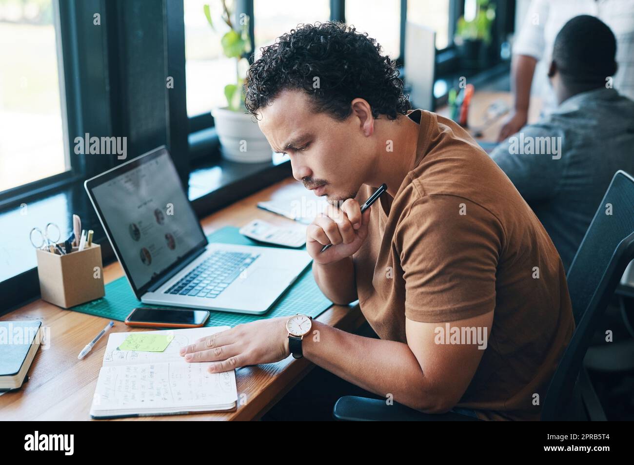 Der Schlüssel zum guten tun ist immer Notizen zu machen. Ein junger Geschäftsmann, der in einem Büro arbeitet. Stockfoto