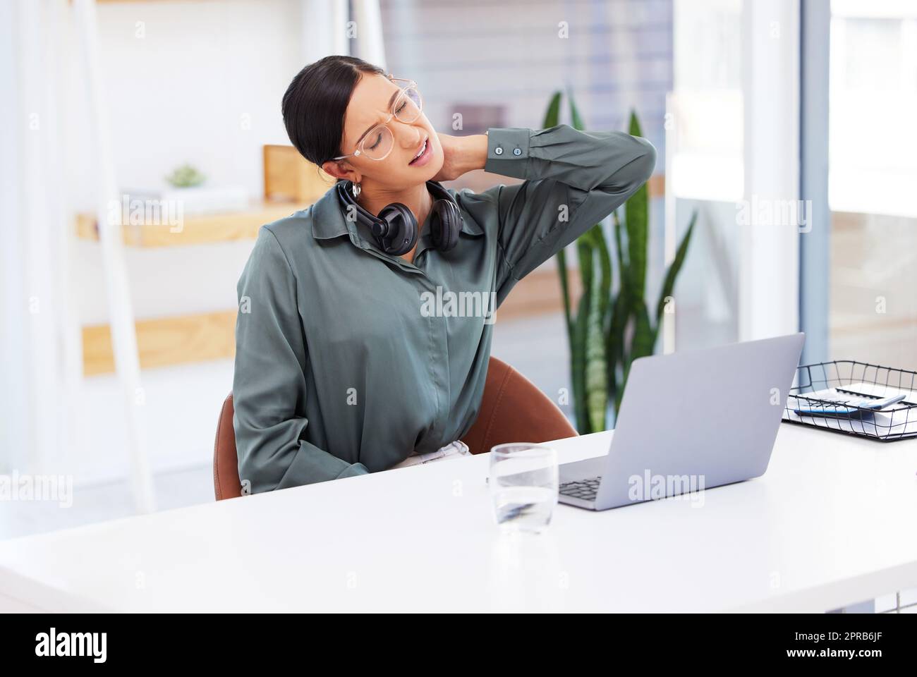 Eine Geschäftsfrau, die in einem Callcenter arbeitet und Nackenschmerzen hat. Stockfoto